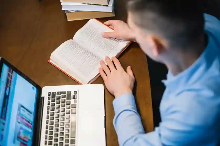 Scholar working at desk while seeking help with PhD dissertation writing tasks.